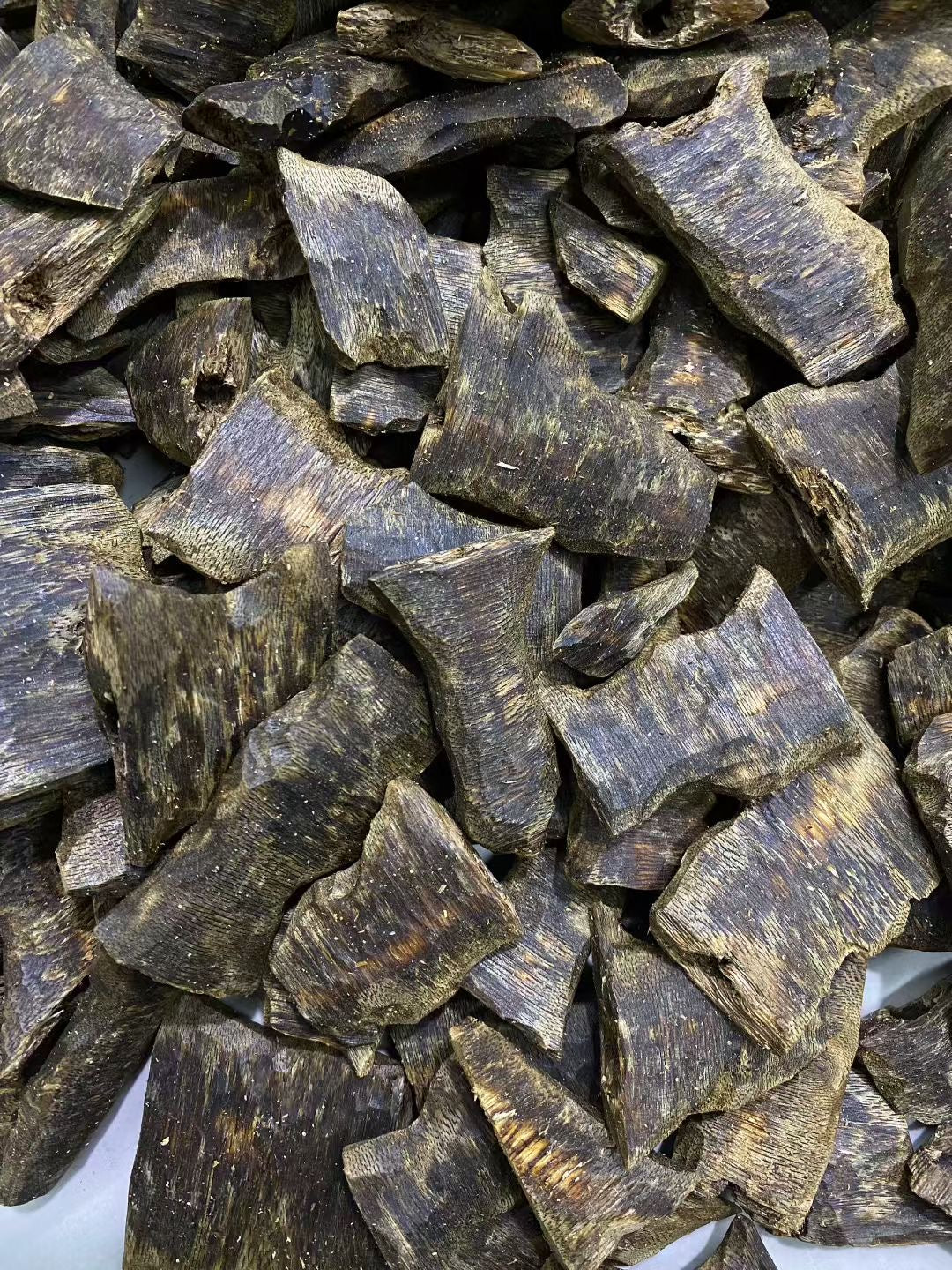 Close-up micro shot of 6A Black Oil Kynam agarwood displaying natural cultivation black resin veins and wet waxy texture