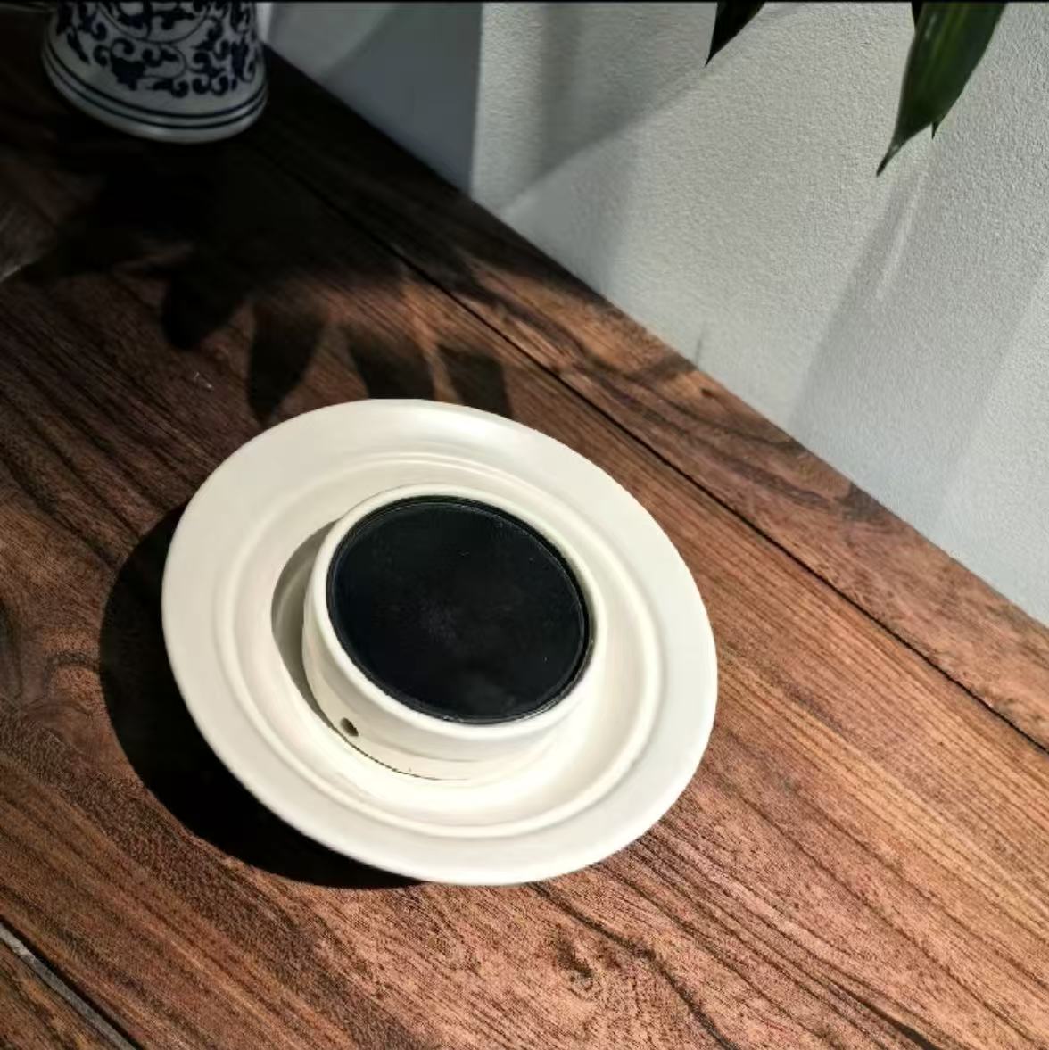 A sleek matte-finished contemporary electronic incense burner sitting on a minimalist wooden cabinet, blending seamlessly as an artistic décor element in a fashionable luxury hom