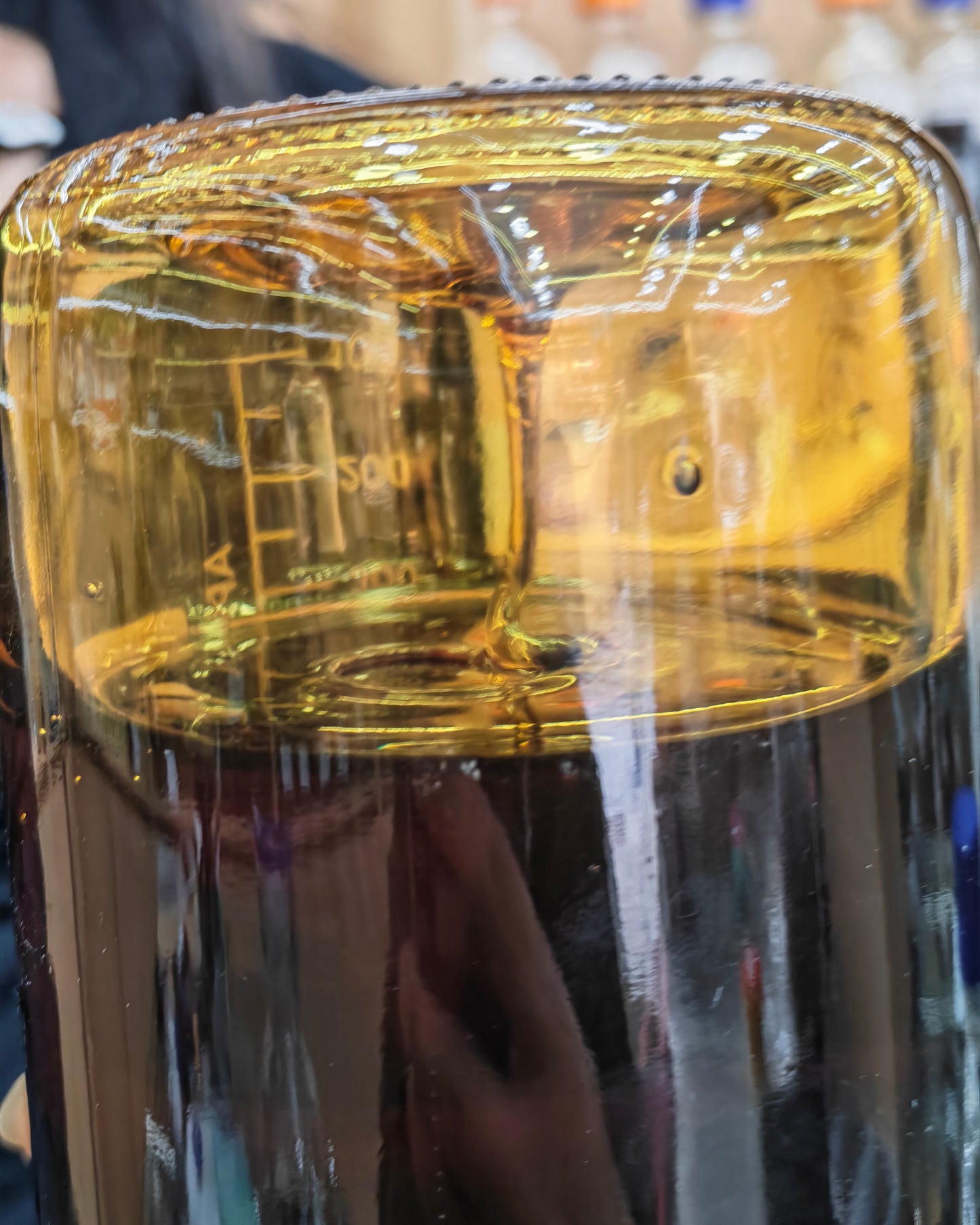 Pure Kynam Oud oil slowly dripping and hanging on the glass wall of the distillation apparatus, showing ultra-high viscosity and crystalline density