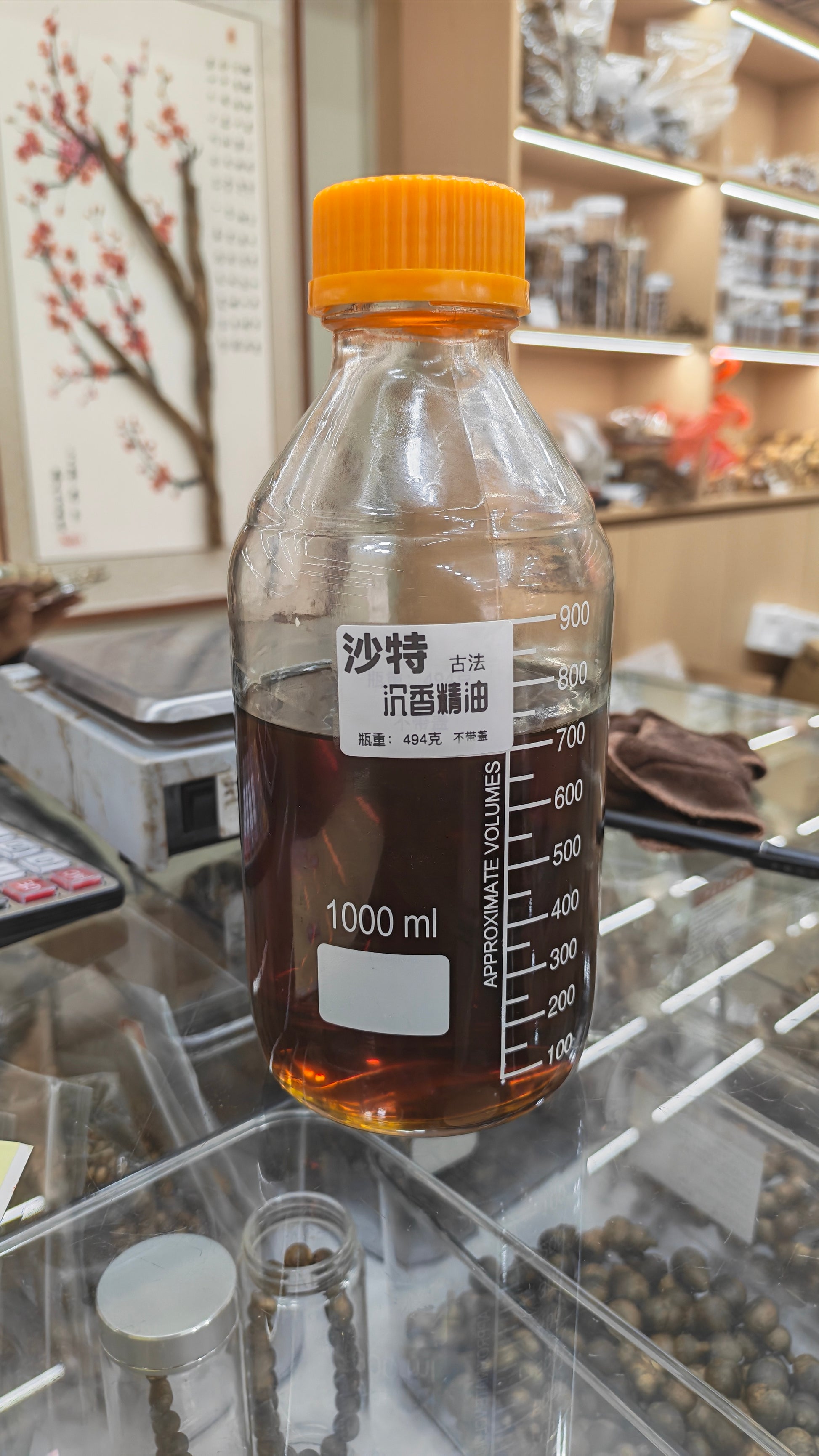A luxury crystal container showcasing the thick, honey-like viscous golden amber texture of decades-aged vintage Mysore sandalwood oil with an intense longan-wood profile